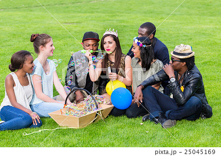 Multicultural group, sitting together on lawn 25045169