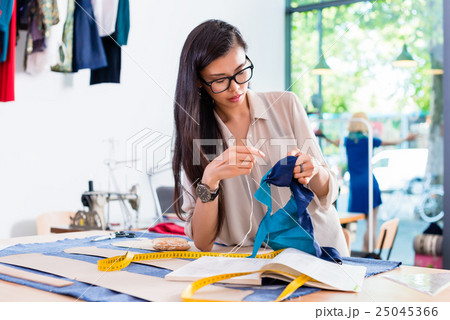 fashion designer woman sewing in her workshop 25045366
