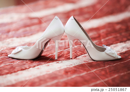 White bridal wedding shoes on red sofa. Marriage 25051867