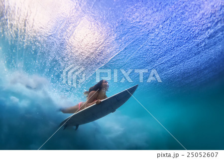 Surfer girl diving under water with surf board Surfer girl diving under water with surf board 25052607