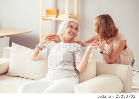 Overjoyed smiling woman resting at home with her 25053702