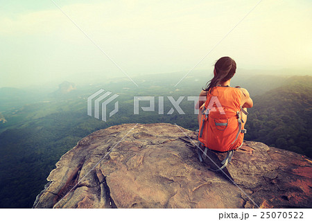 young woman hiker  on mountain peak cliff 25070522