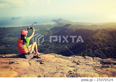 young woman hiker taking photo with smartphone   25070524