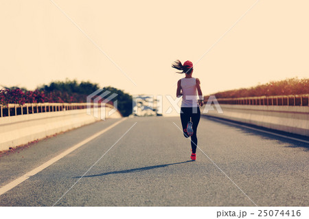 young woman runner running on city road 25074416