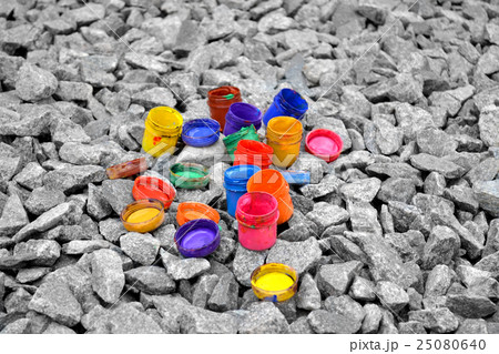 colored small paint cans lie on a gray pebble 25080640