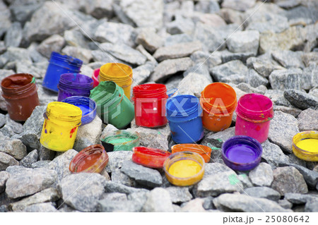 colored small paint cans lie on a gray pebble colored small paint cans lie on a gray pebble 25080642