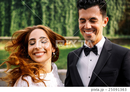 Groom laughs and closes his eyes while bride  25091363
