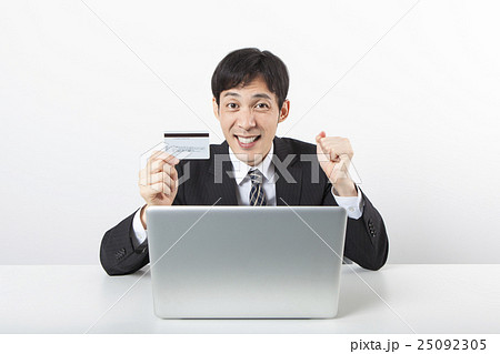 パソコンの前でカードを持つビジネスマン 25092305