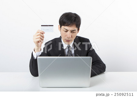 パソコンの前でカードを持つビジネスマン 25092511