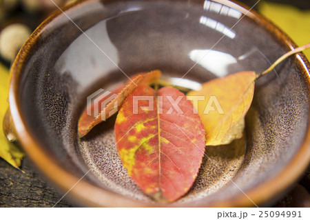 陶器に乗せた赤や黄の落ち葉　秋のイメージ 25094991