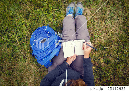 Woman sitting on grass and writing into notebook. Woman sitting on grass and writing into notebook. 25112925