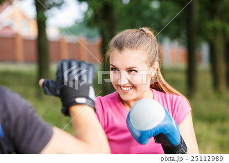 Young sporty woman training boxing with trainer 25112989