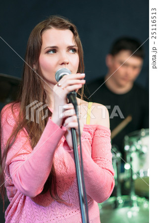 Female singer in pink dress near microphone. 25116513