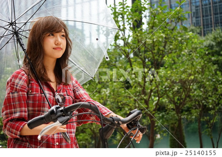 傘をさしながら自転車を運転する若い日本人の女性 傘をさしながら自転車を運転する若い日本人の女性 25140155
