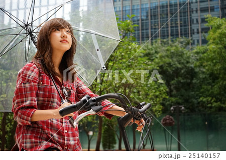 傘をさしながら自転車を運転する若い日本人の女性 傘をさしながら自転車を運転する若い日本人の女性 25140157