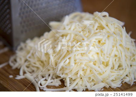 Shredded mozzarella cheese on a cutting board Shredded mozzarella cheese on a cutting board 25141499