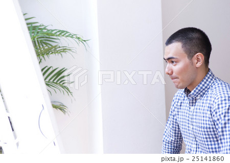 鏡を見る坊主の男性の写真素材