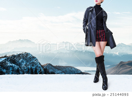 冬のファッションイメージ 黒いレザーコート ショートパンツとブーツ 真冬のアルプス の写真素材