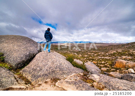 Young woman standing on cliff with outstretched  25165200