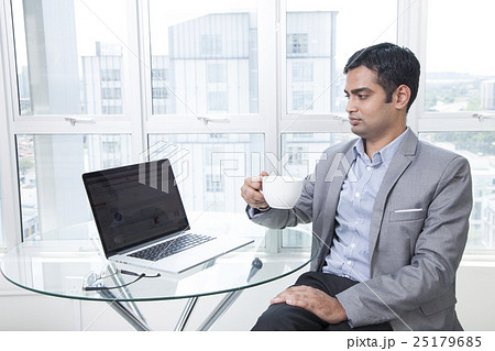 Businessman using laptop holding coffee cup  25179685