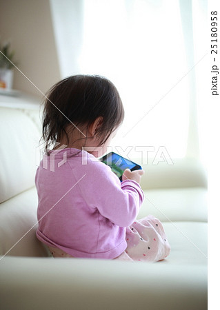 赤ちゃん スマホ 携帯 電話 動画 ベビー 幼児 女の子 1才 1歳 好奇心 興味 の写真素材