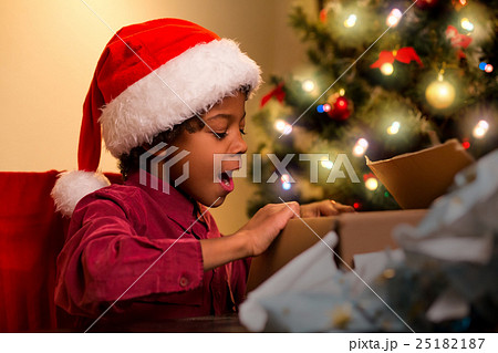 Joyful black boy opens present. Joyful black boy opens present. 25182187