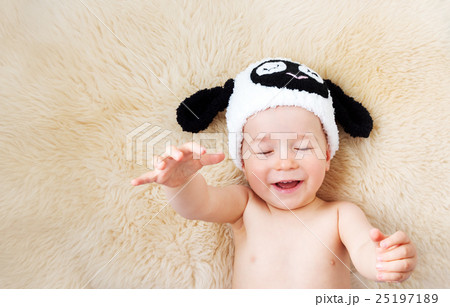 one year old baby lying in sheep hat on lamb wool 25197189
