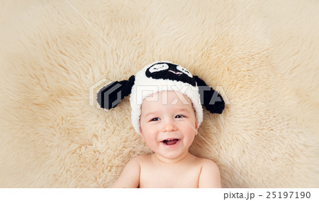 one year old baby lying in sheep hat on lamb wool 25197190