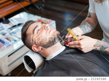 Young man having beard shaven Young man having beard shaven 25197280