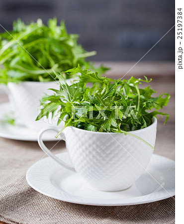 Fresh green arugula in white cup on wooden table 25197384