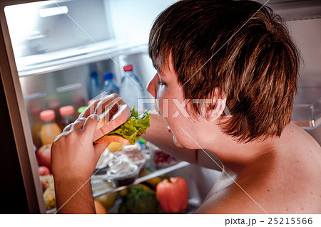 Hungry man holding a sandwich in his hands and standing next to 25215566