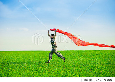 Beautiful young woman jumping on a green meadow 25219360