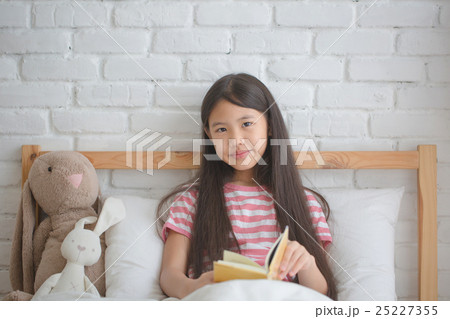 Asian girl reading story book on the bed 25227355