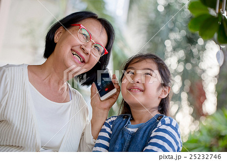 Asian girl calling mobile phone with her grandma Asian girl calling mobile phone with her grandma 25232746