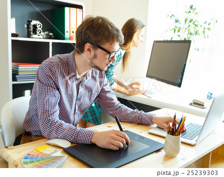 Young artist drawing something on graphic tablet at the office Young artist drawing something on graphic tablet at the office 25239303