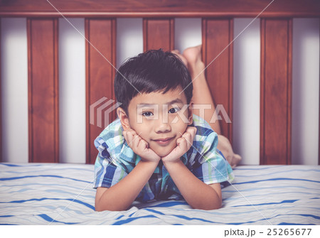 Handsome boy lying on bed. Happy child smiling. 25265677