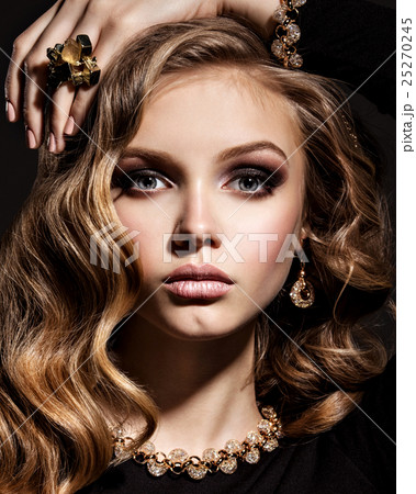 Beautiful woman with long curly hair and gold jewelry 25270245