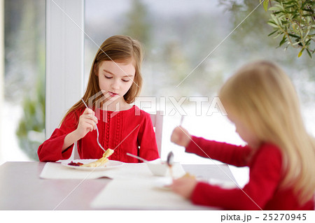Two cute little sisters having crepes for breakfast 25270945