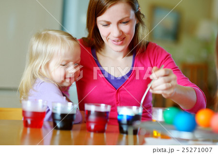 Young mother and her little daughter painting colorful Easter eggs Young mother and her little daughter painting colorful Easter eggs 25271007