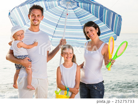 family standing under sun umbrella 25275733