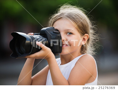 Girl taking pictures with professional camera outdoors Girl taking pictures with professional camera outdoors 25276369