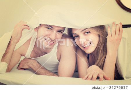 Young couple in bed covered with sheet. 25276637