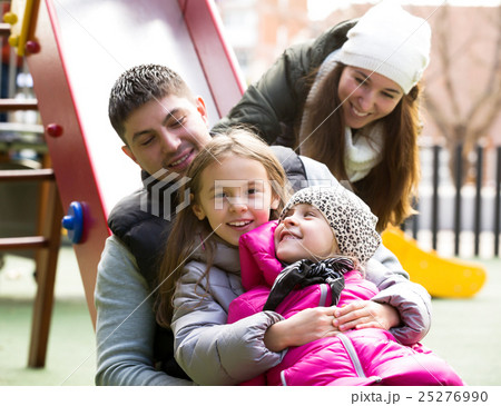 Happy family of four at children's playground 25276990