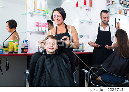 Smiling boy getting hairdo by female hairdresser 25277134