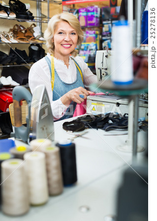 happy middle-aged woman tailor using sewing machine happy middle-aged woman tailor using sewing machine 25278136