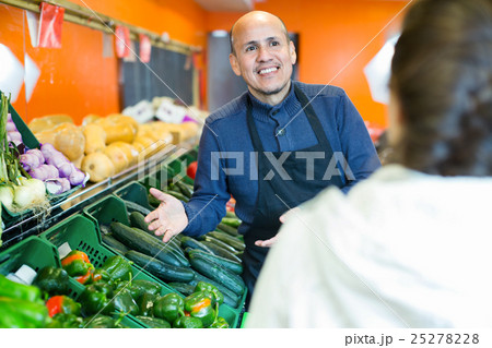 Young woman buying seasonal vegetables from mature seller Young woman buying seasonal vegetables from mature seller 25278228