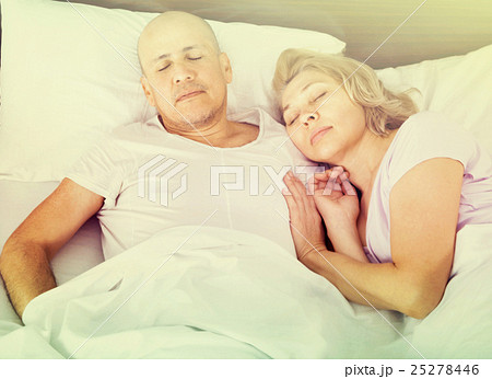 Portrait of charming ordinary mature couple napping in bed 25278446