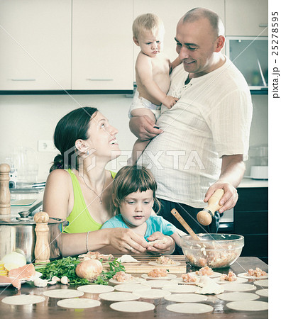family of four making fish dumplings (pelmeni) at home kitchen 25278595