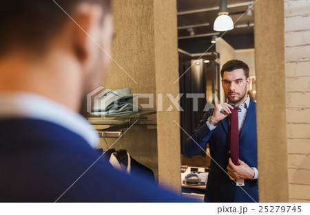 man trying tie on at mirror in clothing store man trying tie on at mirror in clothing store 25279745