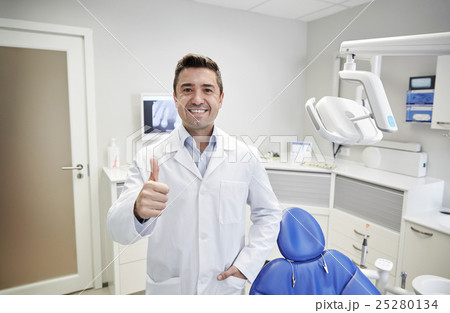 happy male dentist showing thumbs up at clinic happy male dentist showing thumbs up at clinic 25280134